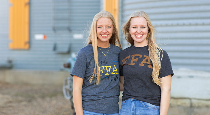 Two young women standing in front of a grain bin 